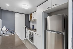 Eine moderne Küche mit Edelstahlgeräten, weißen Schränken und einer grauen Wand.