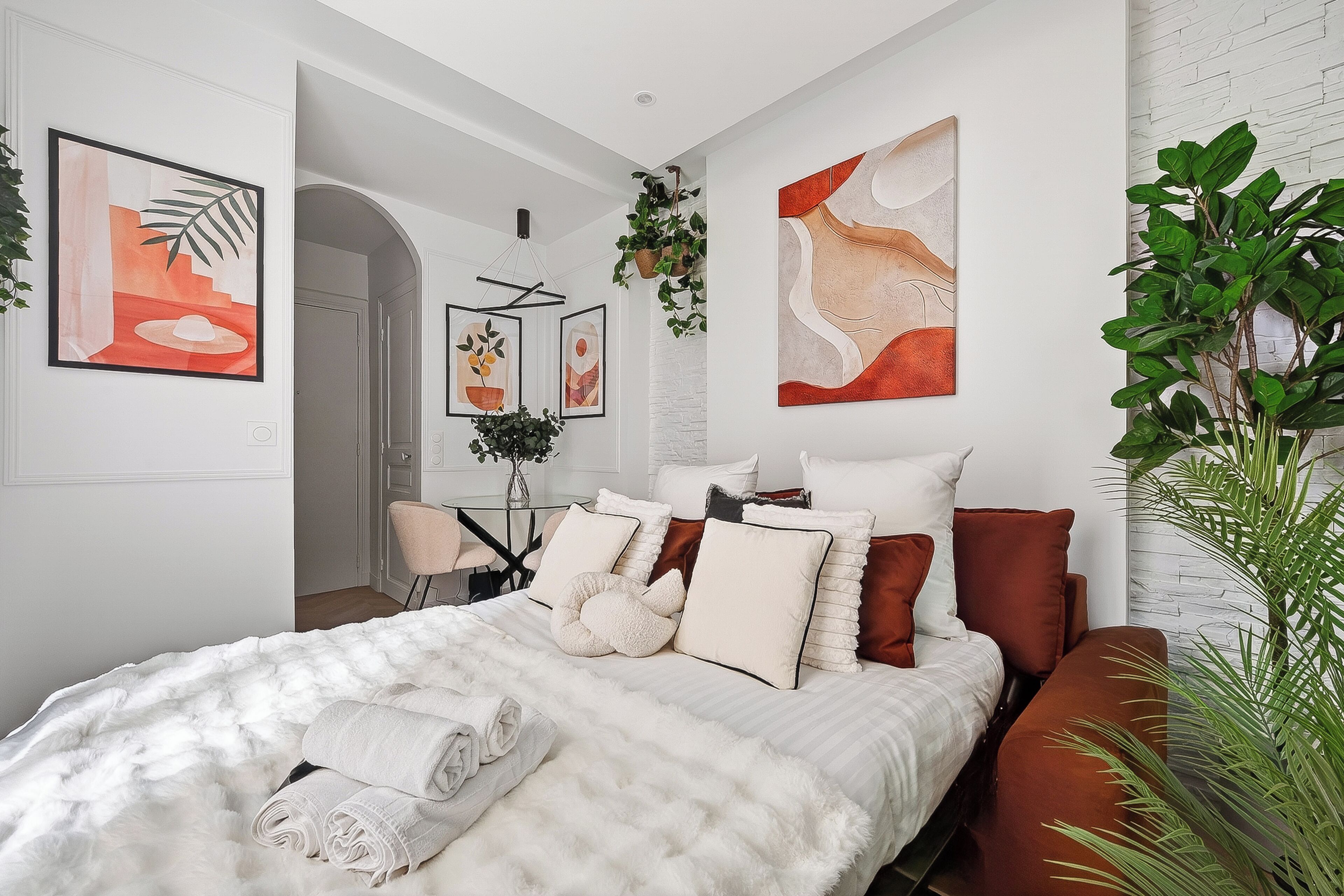 A modern bedroom with a large bed, a sofa, and a dining area with a table and chairs.