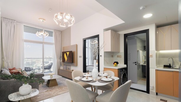 Una sala moderna con sofá, mesa de comedor y sillas, una cocina con lavaplatos y armarios, y un gran ventanal con vistas a la ciudad.
