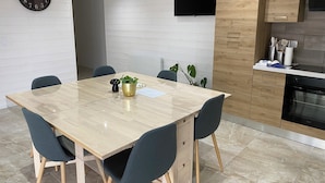 A modern kitchen with a wooden cabinet, a black oven, and a dining area with a marble table and chairs. - Spacious detached apartment in quiet area (Allouagne)