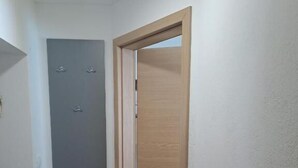En hall med en trädörr och en grå vägg med tre små, otydliga föremål.