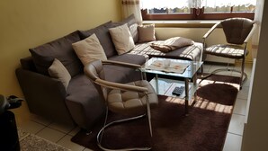 A living room with a sofa, armchair, coffee table, and a chair. - Lissis Apartment in Karlshagen (Karlshagen)