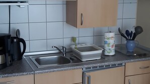 A kitchen with a sink, a coffee maker, a dish rack, and a roll of paper towels. - Lissis Apartment in Karlshagen (Karlshagen)