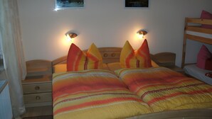 A double bed with striped bedding, two bedside tables, a wooden headboard, and wall-mounted lamps. - Lissis Apartment in Karlshagen (Karlshagen)