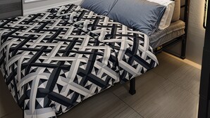 Une chambre à coucher moderne avec une couvre-lit à motifs géométriques, une porte-fenêtre coulissante et une armoire intégrée.