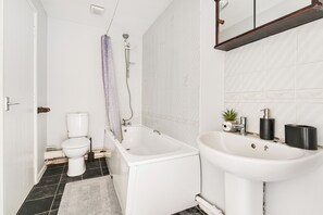 A bathroom with a white bathtub, a toilet, and a sink. - Spacious 2 bed house in London - Off street parking and Garden (London)