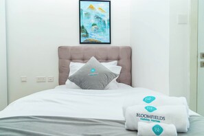 A hotel room with a bed, a painting on the wall, and pillows with the hotel logo. - Bloomfields 2BR Duplex Canal View Ra (Abu Dhabi)