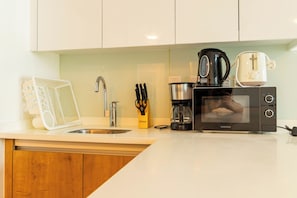 A kitchen with a sink, a coffee maker, a microwave, and a toaster. - Bloomfields 2BR Duplex Canal View Ra (Abu Dhabi)