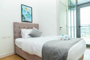 A hotel room with a bed, a painting, and a view through a glass door. - Bloomfields 2BR Duplex in Raha Lofts - Raha (Abu Dhabi)