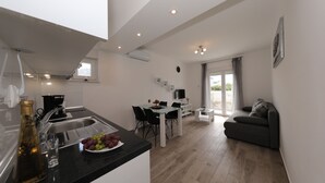 A modern kitchen with a dining area, a sofa, and a TV.