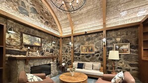 Una sala de estar acogedora con paredes de piedra, una chimenea, un sofá y una mesa de centro.
