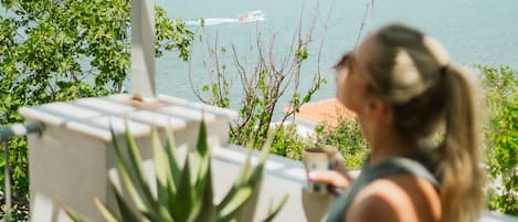 A person sitting on a balcony overlooking a body of water with a boat in the distance.