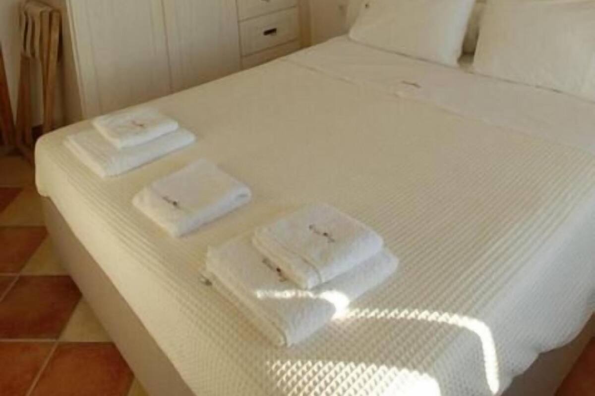 A bedroom with a bed, white curtains, a wardrobe, and a small decorative item on the wall.
