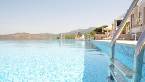 Une magnifique piscine à débordement d’un bleu profond, avec une vue sur les montagnes en arrière-plan.
