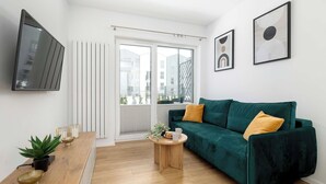 Una sala de estar moderna con un sofá verde, una mesa de centro de madera y un televisor montado en la pared.