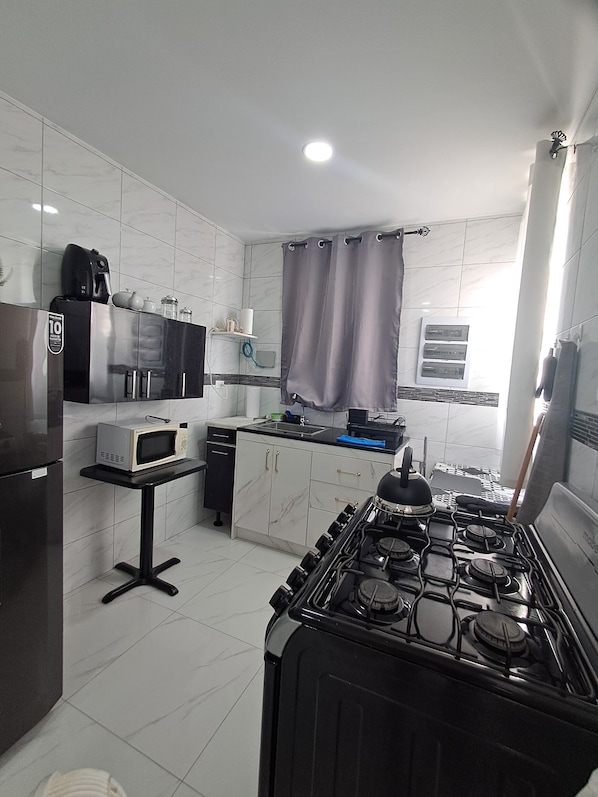 A modern kitchen with a stove, microwave, and refrigerator. - Lovely 2-bedroom Private house with AC in perfect Oranjestad location (Oranjestad)