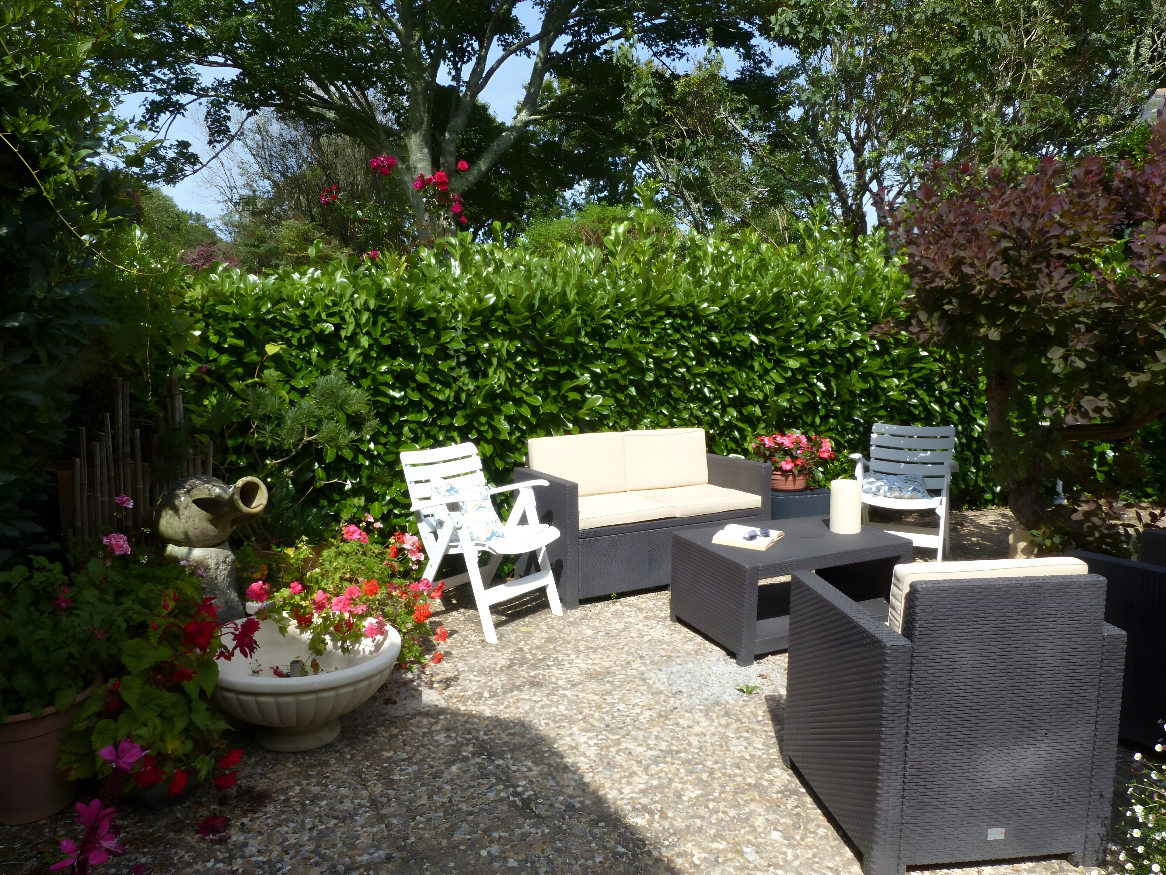 Een terras buiten met een bank, stoelen en een tafel.
