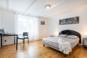 A bedroom with a bed, a desk, a chair, a window with curtains, and a painting on the wall. - Maison Ty an traon – Spacious Renovated House 4km from Bénodet (Clohars-Fouesnant)