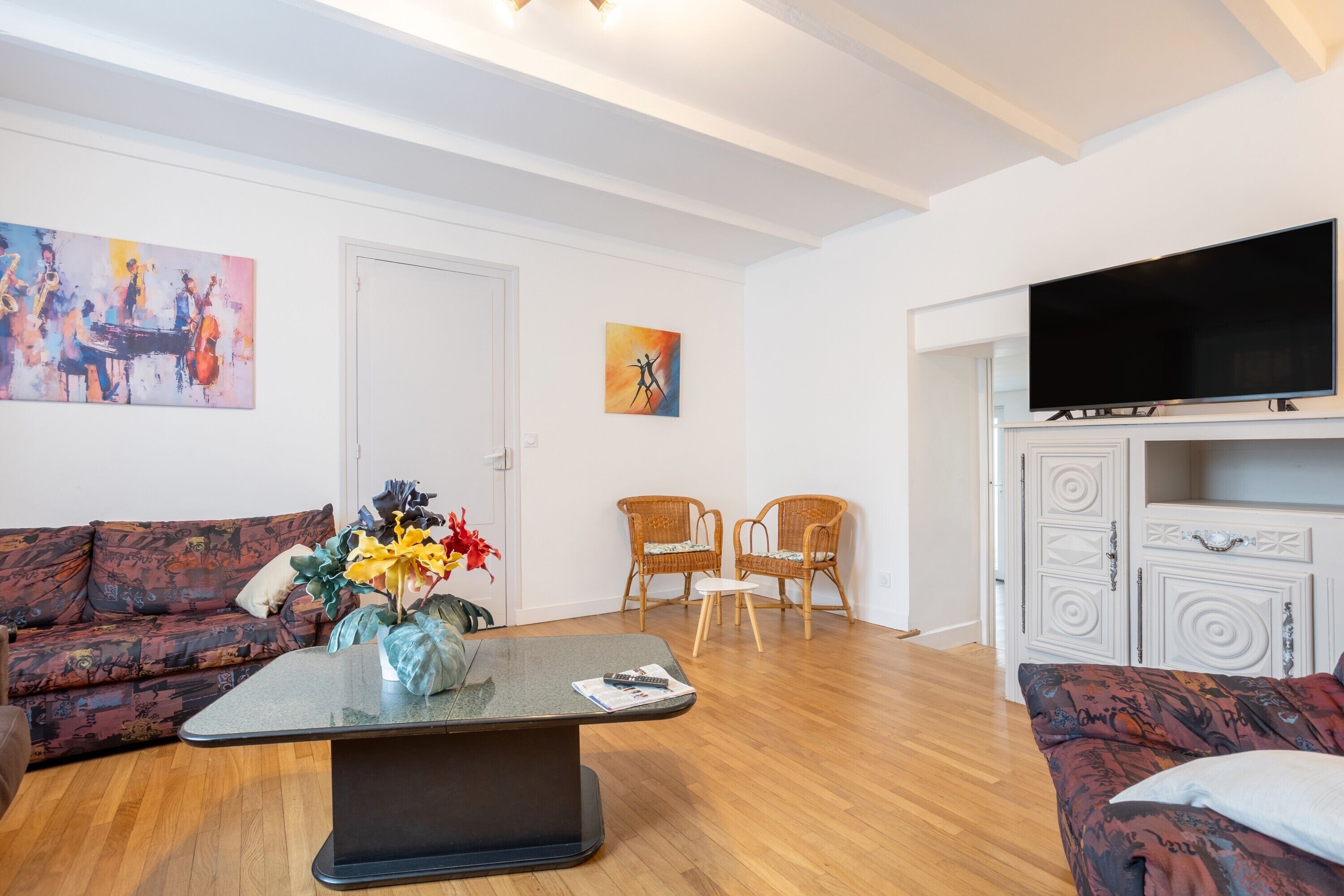 Un salon avec un canapé, une table basse, un téléviseur et deux fauteuils.