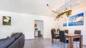 Un salon moderne comprenant un canapé, une table à manger, des chaises et des œuvres d’art accrochées aux murs.