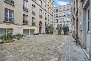 A courtyard with cobblestone flooring, a building labeled "ENTREPRISE EDOUARD," and bicycles parked along the side. - Duplex Center of Paris (Paris)