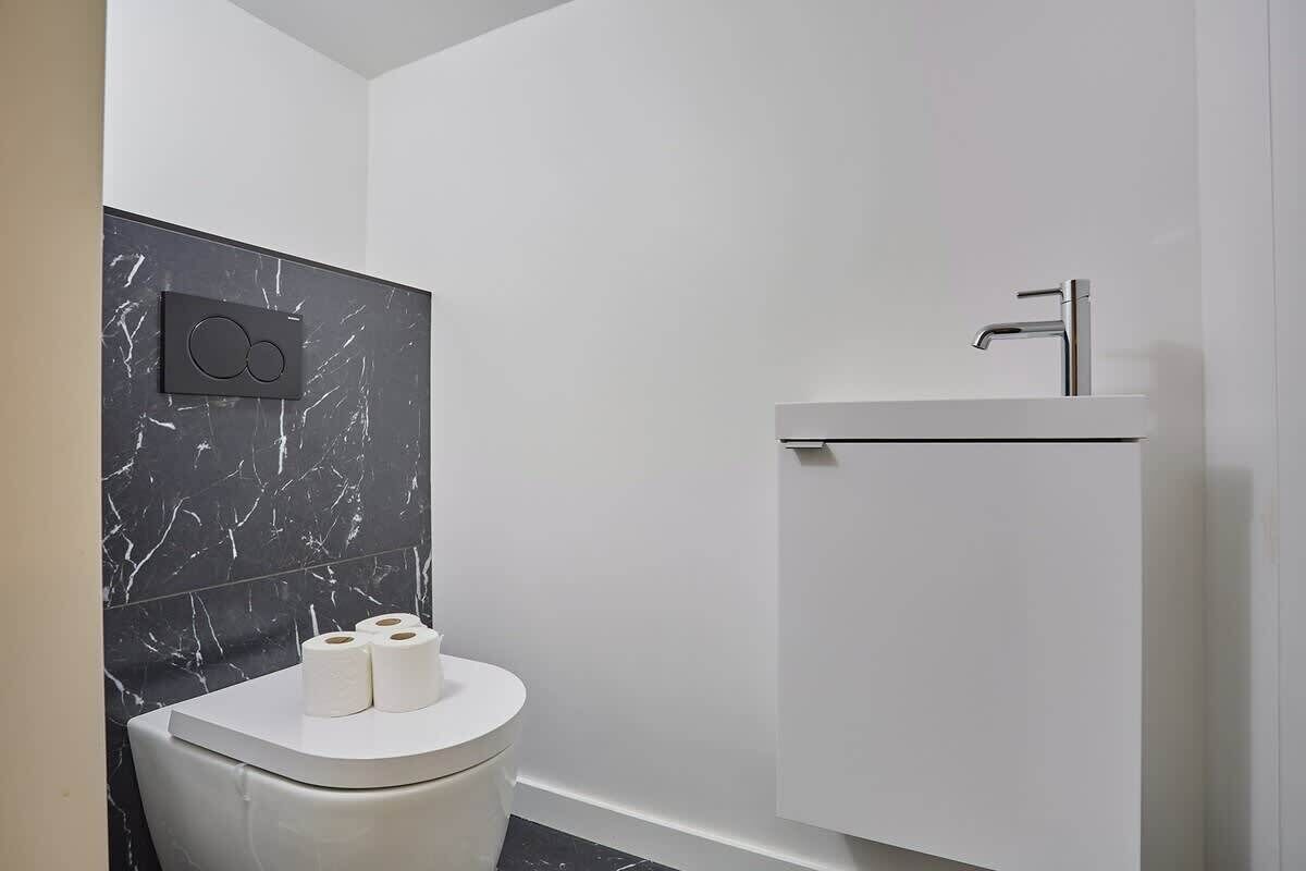Ein modernes Badezimmer mit Toilette, Waschbecken und Dusche.