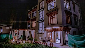 Un edificio de varios pisos con un patio interior, ventanas amplias y un espacio de estar al aire libre techado.