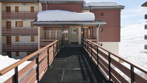 A hotel entrance with a covered walkway, wooden railings, and snow on the roof.