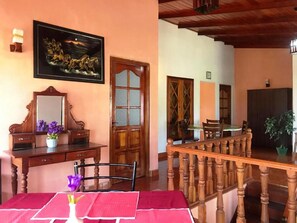 Una habitación con un escritorio de madera, una silla, una mesa con mantel rojo, un espejo y un cuadro de caballos.