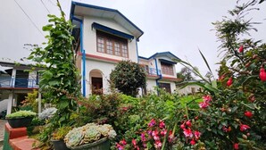 A two-story building with a balcony, surrounded by lush greenery and flowering plants. - Aurora Residence Nuwara (Nuwara Eliya)