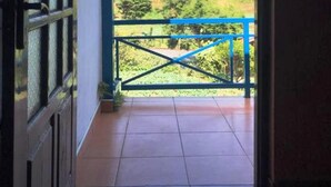 An open door leading to a balcony with a view of a green landscape and a mountain. - Aurora Residence Nuwara (Nuwara Eliya)
