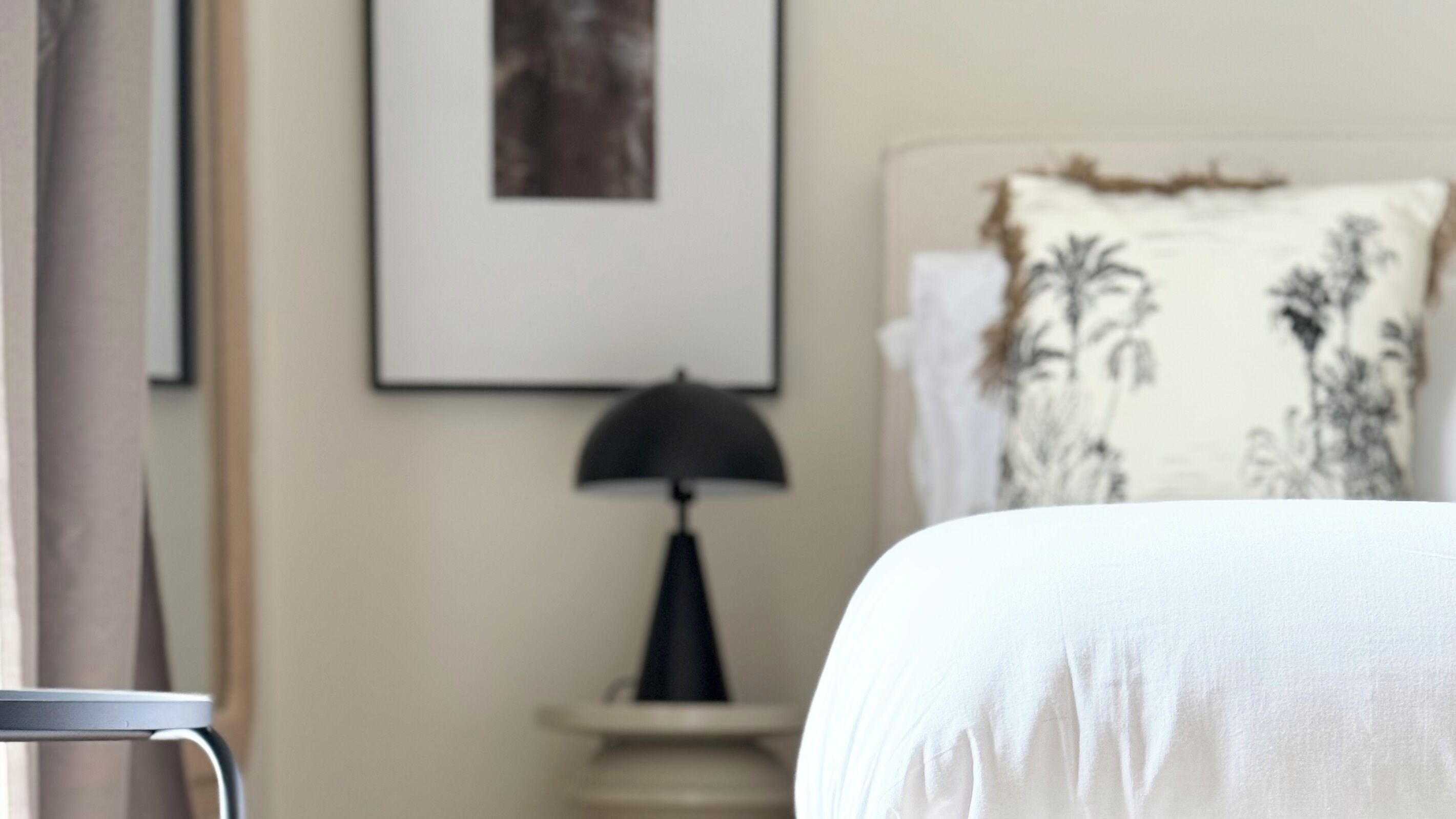 A bedroom with a bed, a nightstand with a lamp, and a framed picture on the wall.