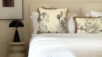 Un lit avec une literie blanche et deux coussins décoratifs ornés de motifs floraux.