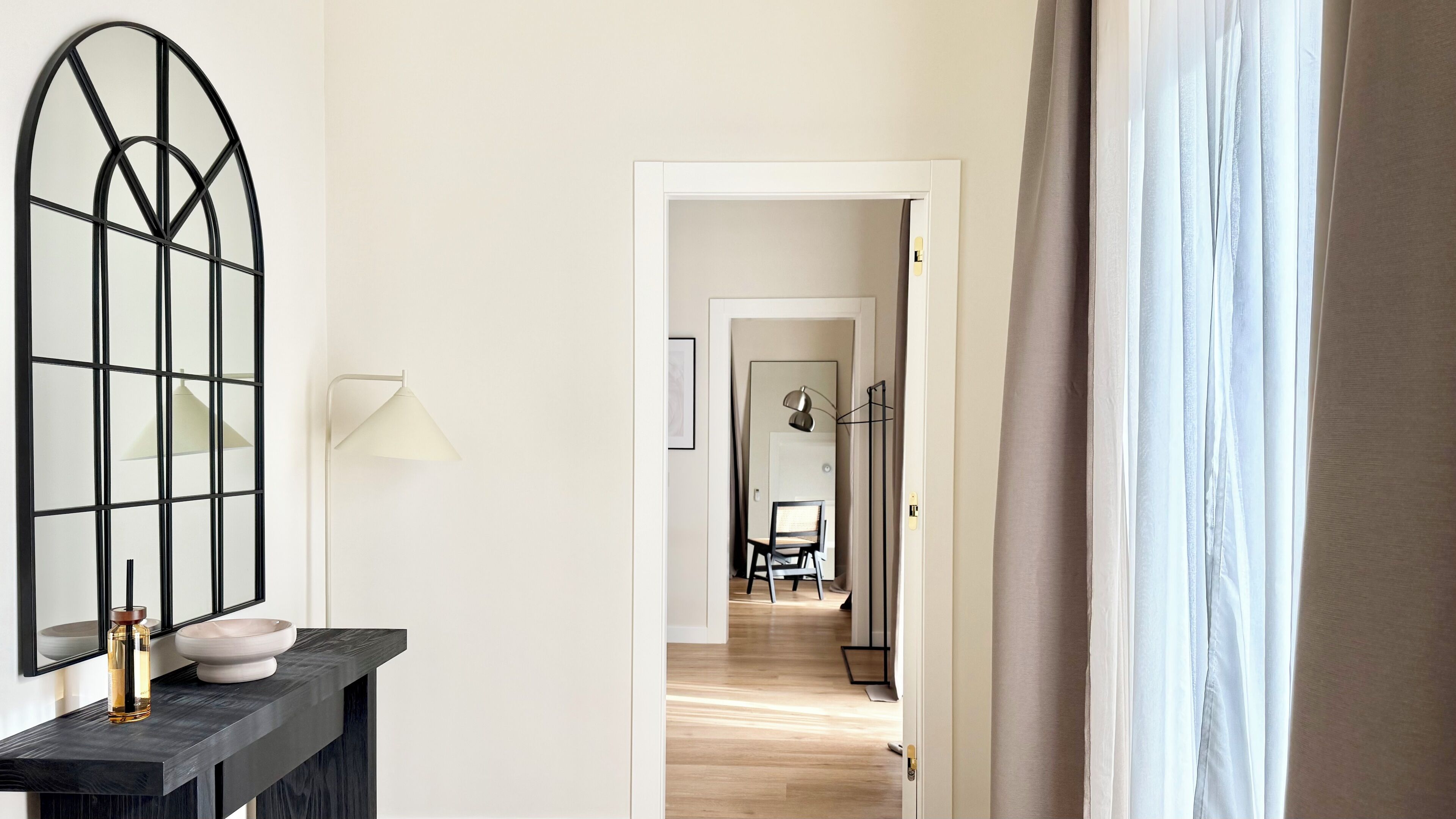 A hallway with a modern light fixture, a mirror, and a door leading to a dining area.