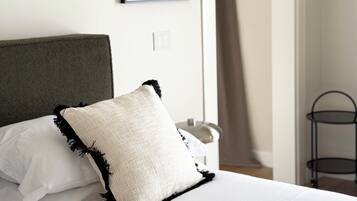 A bed with a green headboard, white bedding, and a white pillow with black trim.