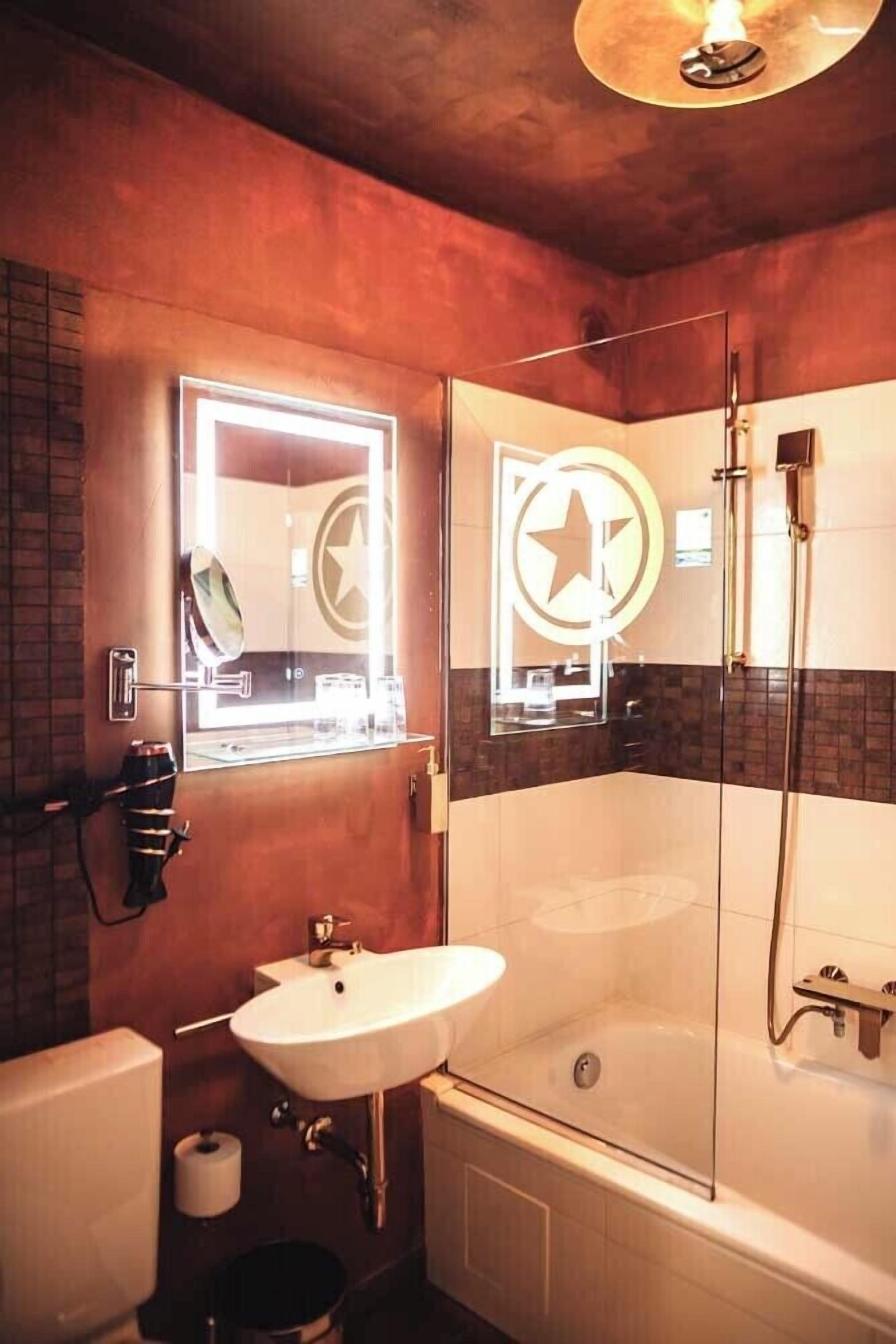 Un baño con cabina de ducha de vidrio, un lavamanos y un espejo con diseño de estrella.