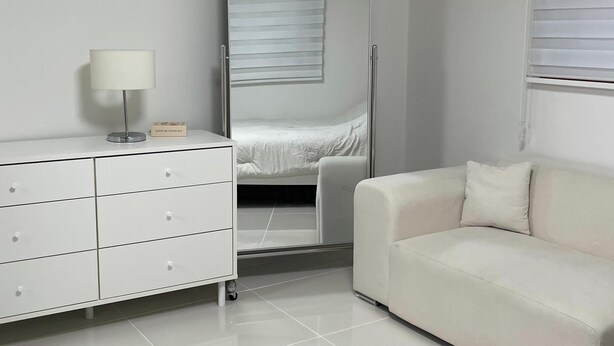 Une chambre d’hôtel équipée d’un lit, d’un canapé, d’une commode, d’une lampe et d’un appareil de climatisation.