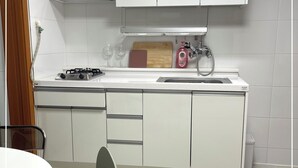 Une cuisine moderne avec des meubles blancs, une cuisinière à gaz, un évier et une planche à découper en bois.