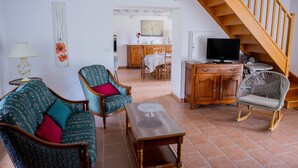 Una sala de estar con sofá, sillas, una mesa de centro, televisor y una escalera de madera.