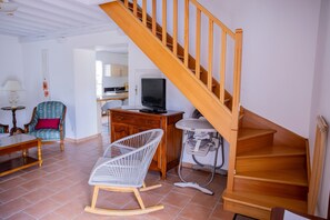A living room with a wooden staircase, a rocking chair, a dining table, and a television. - Gîte at the Gates of Chambord (Crouy-sur-Cosson)