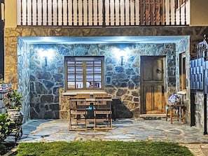 A stone-walled outdoor seating area with a table and chairs, a window, and a door. - Ländliches Anwesen "Mar y Montaña" (Meer und Berge) by Interhome (Lamuño)