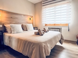 A neatly made bed with pillows and rolled towels, a wooden headboard, a bedside table, and a radiator. - Ländliches Anwesen "Mar y Montaña" (Meer und Berge) by Interhome (Lamuño)