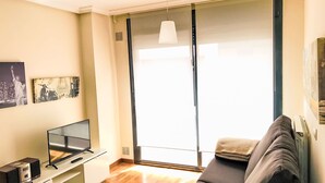 A living room with a sofa, a TV, and a window with curtains. - mit Aussicht in Luanco by Interhome (Luanco)
