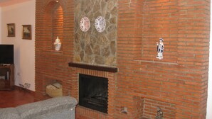 A living room with a brick fireplace, decorative plates, and a small statue. - "Remedios" mit Terrasse by Interhome (Cuevas del Becerro)