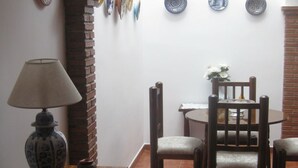 A dining area with a table and chairs, a lamp, and decorative plates on the wall. - "Remedios" mit Terrasse by Interhome (Cuevas del Becerro)