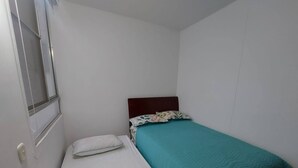 A small, single-bed room with a wooden headboard, white bedding, and a teal bedspread. - South of Cali Quiet Modern (Cali)