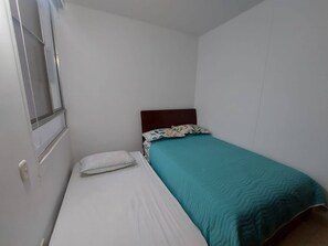 A small, single-bed room with a wooden headboard, white bedding, and a teal bedspread. - South of Cali Quiet Modern (Cali)