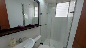 A bathroom with a white sink, toilet, and glass shower enclosure. - South of Cali Quiet Modern (Cali)