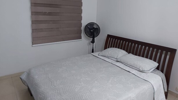 A bedroom with a bed, a standing fan, and a window with blinds. - South of Cali Quiet Modern (Cali)