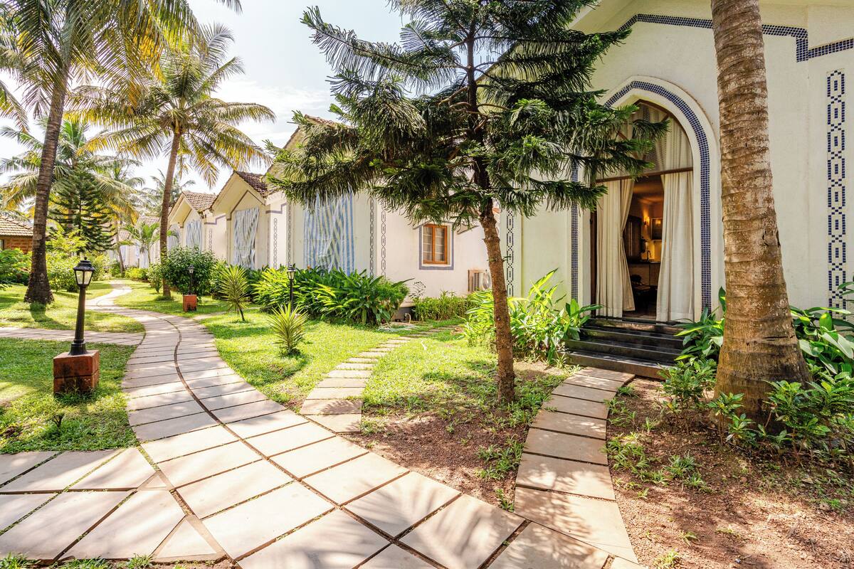 A pathway leading to a building with a tiled entrance and a palm tree in the foreground.